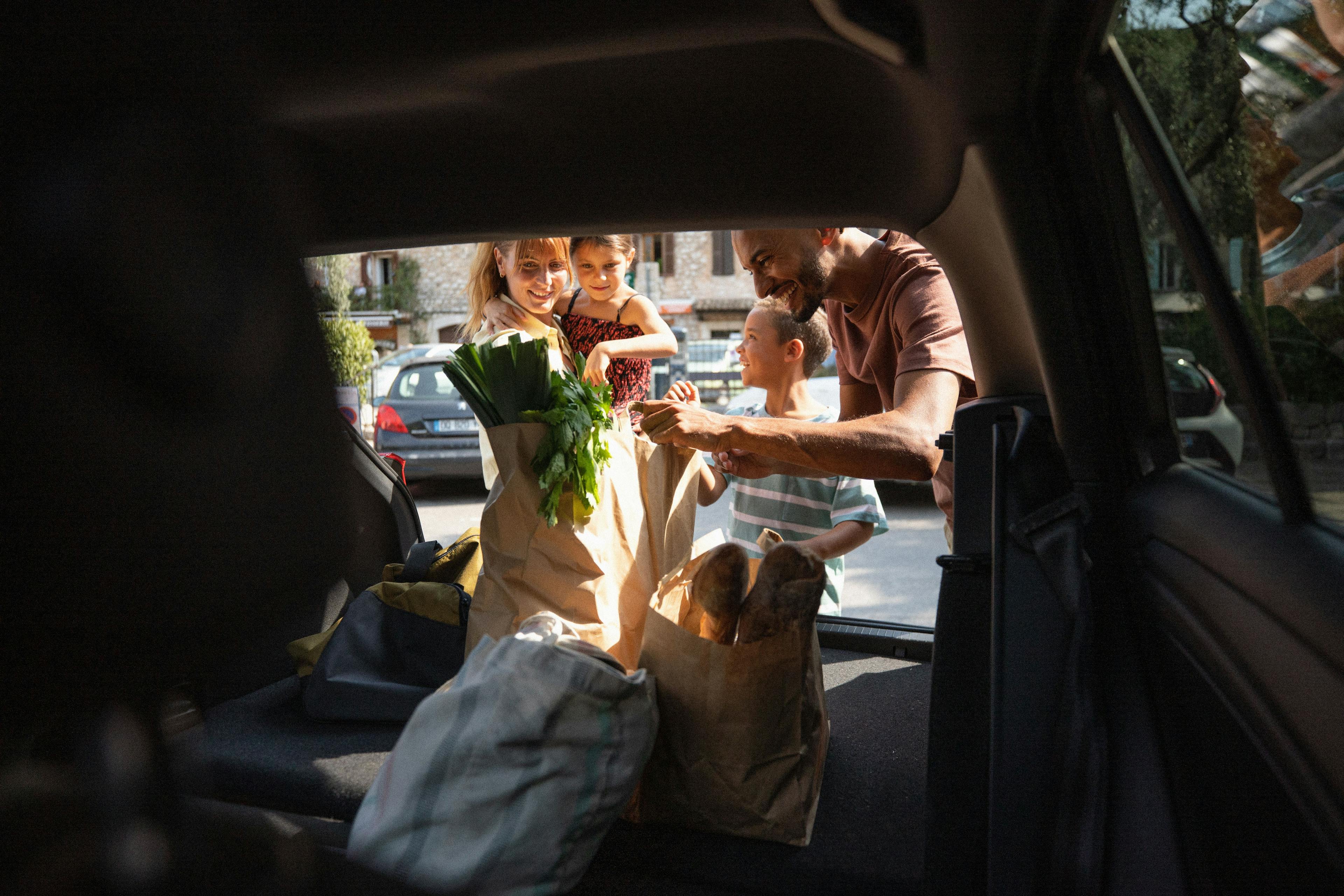 une famille range ses courses dans le coffre d'une voiture